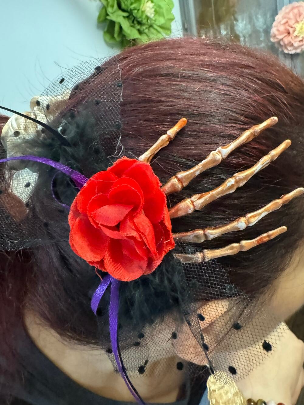 Red rose hair clip with black feathers and skeleton hand design